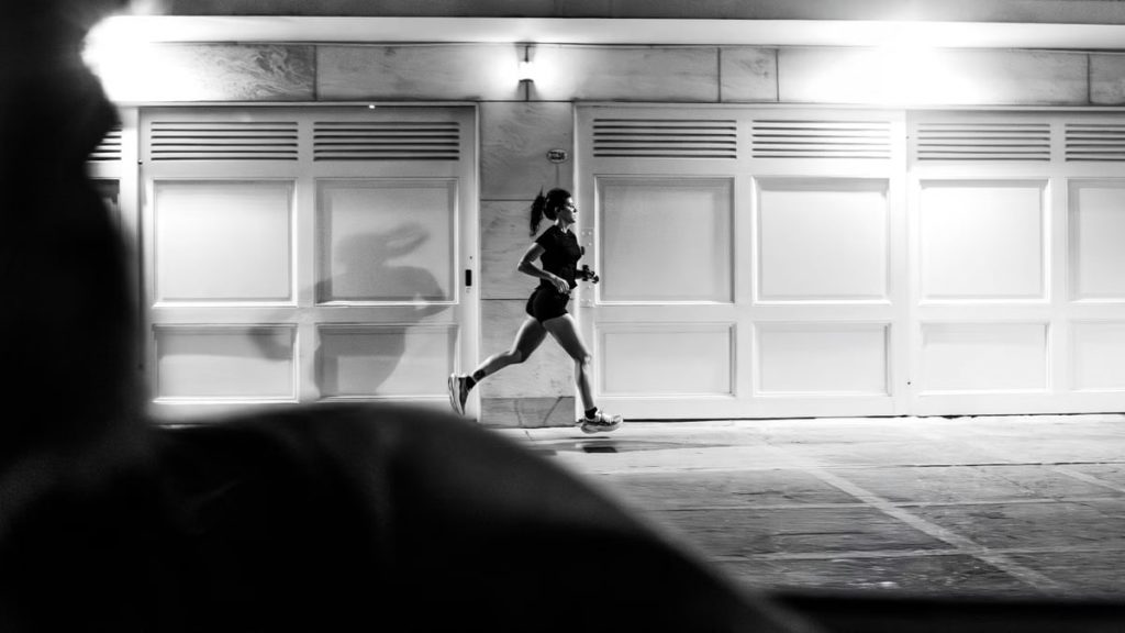 A woman running at night in Buenos Aires, showcasing urban life in black and white.