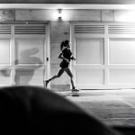 A woman running at night in Buenos Aires, showcasing urban life in black and white.