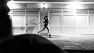 A woman running at night in Buenos Aires, showcasing urban life in black and white.