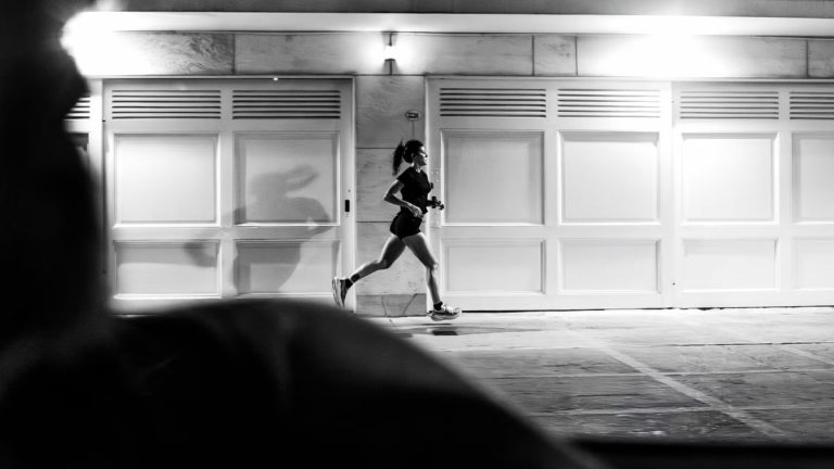 A woman running at night in Buenos Aires, showcasing urban life in black and white.